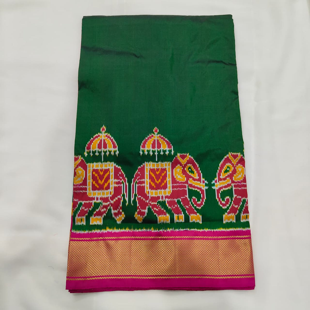 Bottle green ikat silk saree with pink elephant motifs and a pink and gold zari border
