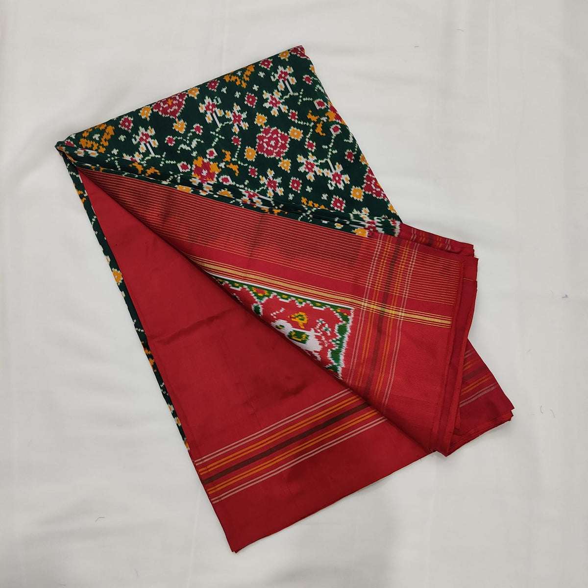 Deep green ikat silk saree with all-over red and yellow Patola florals and a red border